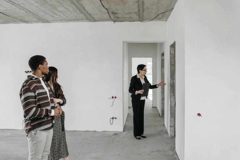 A couple explores an unfinished apartment with a real estate agent, considering property purchase options.